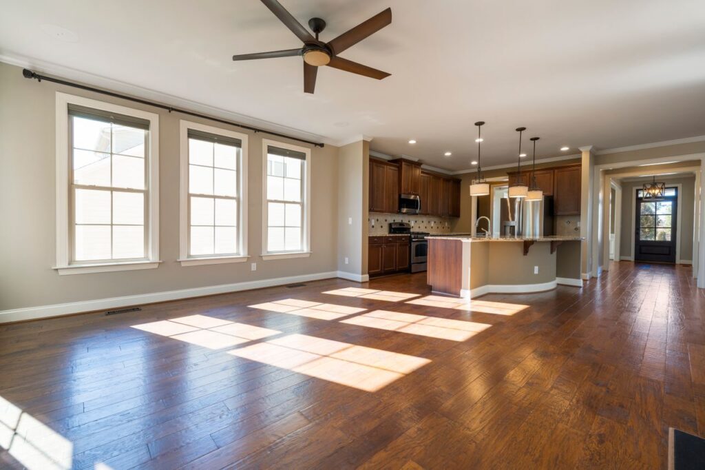 A spacious sunlit kitchen and living area with hardwood floors and modern appliances.